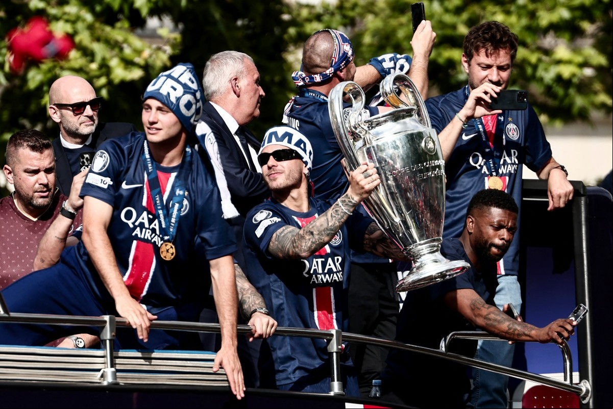 Paris Saint-Germain's French defender #21 Lucas Hernandez (C) holds the UEFA Champions League Trophy during a parade on the Champs-Elysees avenue in Paris on June 1, 2025, a day after PSG won the 2025 UEFA Champions League final football match against Inter Milan in Munich. (Photo by Thibaud MORITZ / AFP)