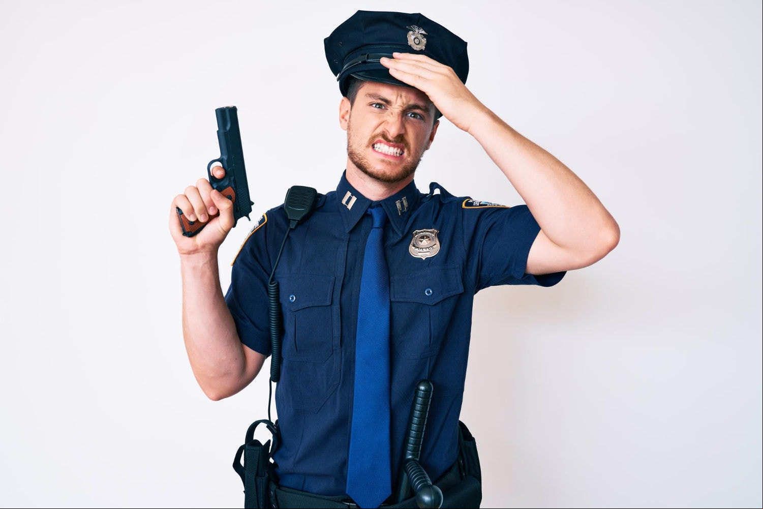 Policial com arma leva mão à cabeça