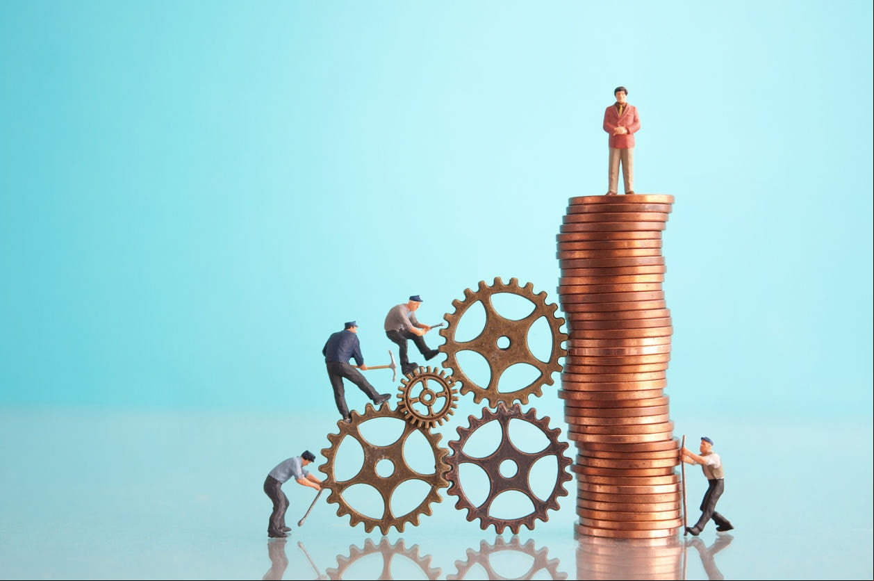 Miniature businessman on top of a pile of coins with construction workers, leadership, success concept