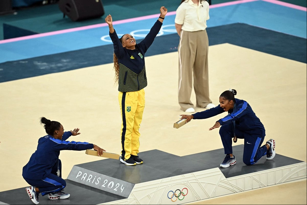 Rebeca Andrade e Simone Bales Olimpíada 2024 A ginasta brasileira Rebeca Andrade é reverenciada pelas norte-americanas Simone Biles e Jordan Chile após conquistar medalha de ouro no solo da ginástica artística no dia 5 de agosto