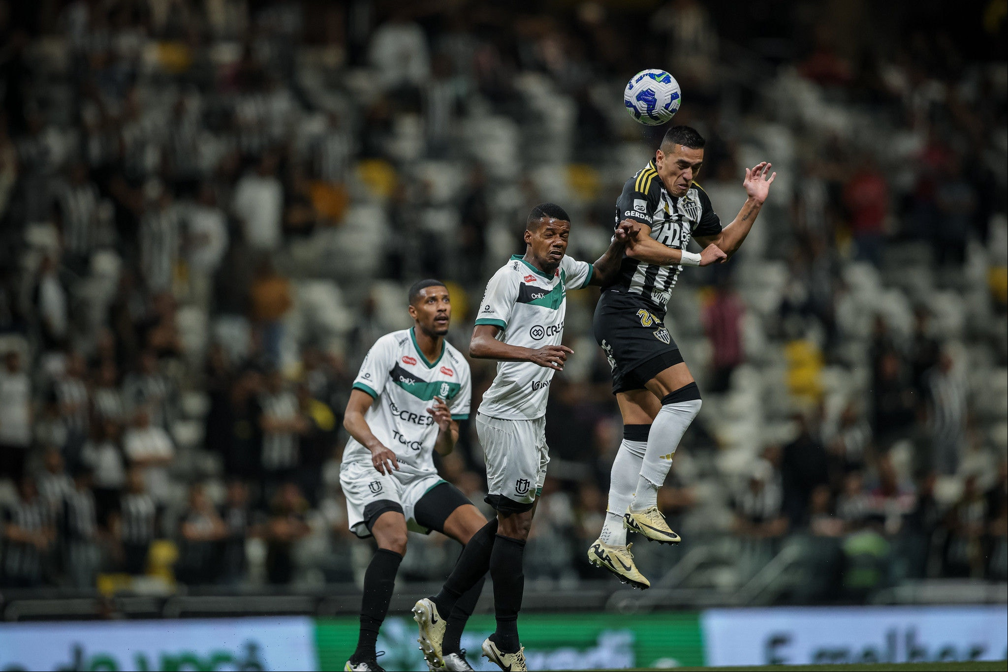 Cuello salta para tentar disputar a bola com defensor do Maringá durante partida disputada na Arena MRV