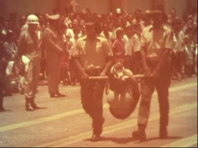 Foto antiga mostra, durante a ditadura militar, policiais desfilando com um homem preso em um pau de arara, instrumento usado para torturar presos durante o regime Esta é a única cena registrada no Brasil que mostra, em um evento público, um ato de tortura