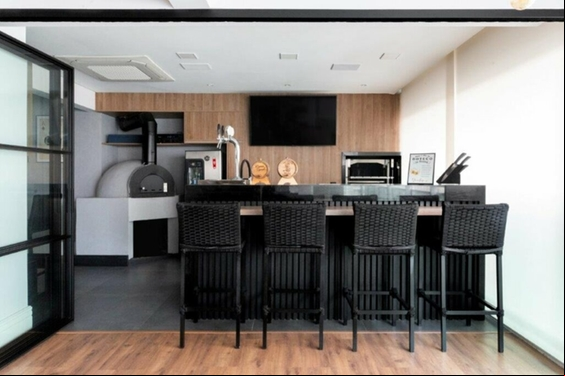 Cozinha com bancada preta e parede revestida com madeira